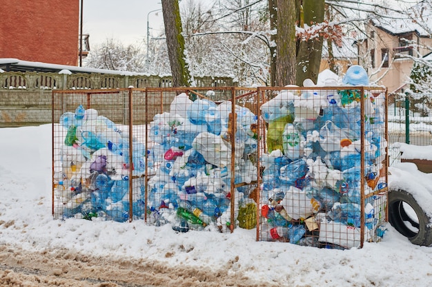 Three open dumpsters full of plastic bottles and bags. plastic\
waste in large trash cans. city dump in winter street.