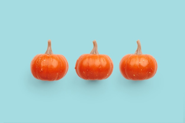 パステル カラーの背景に 3 つのオレンジ色のカボチャ ハロウィーンのカボチャの背景秋のコンセプト