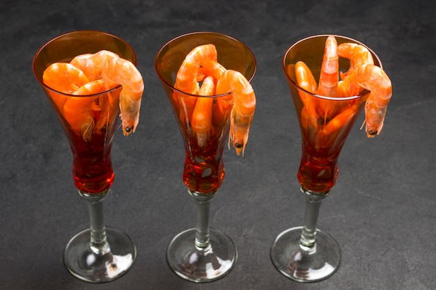 Photo three orange wine glasses with shrimp.