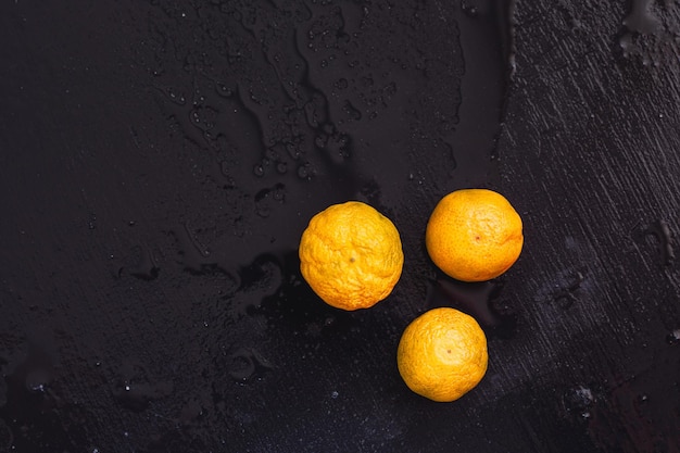 Three oranges on a wooden table on a dark background Mandarines copy space Top view