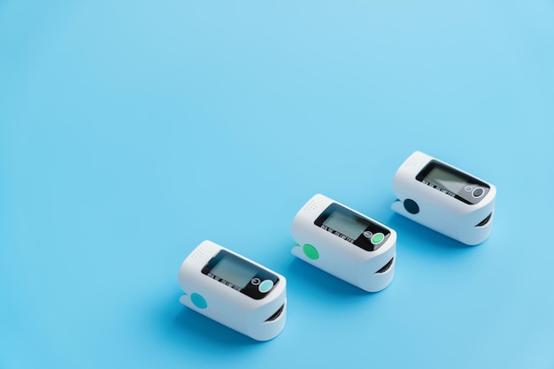 Three oximeters on a blue background. Medical devices for measuring the level of blood oxygen saturation