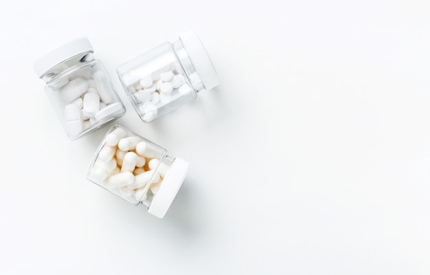 Three packages with various white pills and capcules on a white background. Health concept.  Top view.