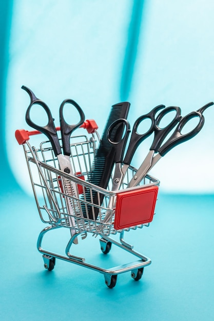 Three pairs of scissors and one comb lie in a mini basket on a blue background