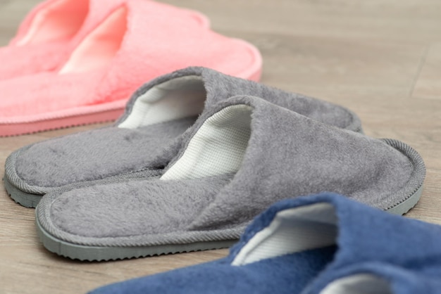 Three pairs of slippers on the floor Colourful home footwear on the floor