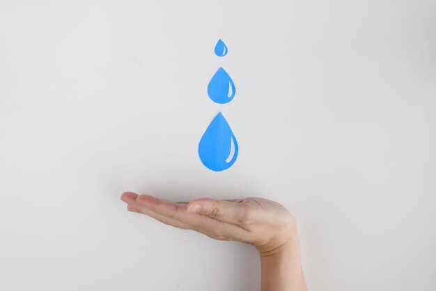 Foto la forma di tre gocce d'acqua di carta è tenuta dalla mano della donna per risparmiare acqua per incoraggiare la giornata mondiale dell'acqua