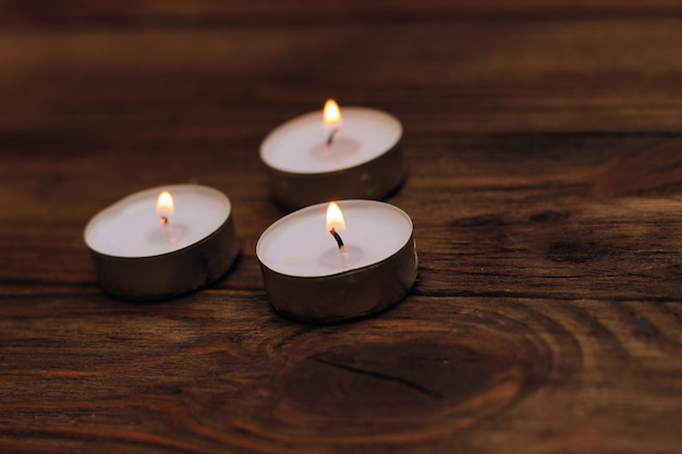 Three paraffin floating candles on a wooden table