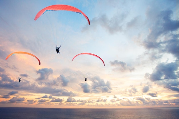 Three paragliders against the sky over with beautiful sunset