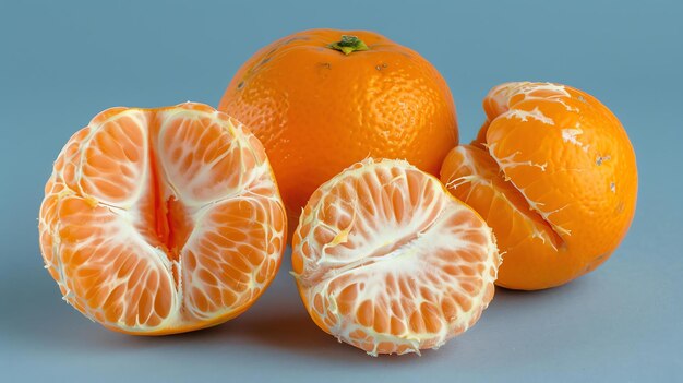 Three peeled and one whole tangerines on a blue background The tangerines are arranged in a visually pleasing way and the image is welllit