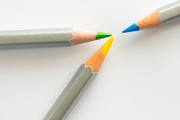 Three pencils: blue, yellow and green. White background