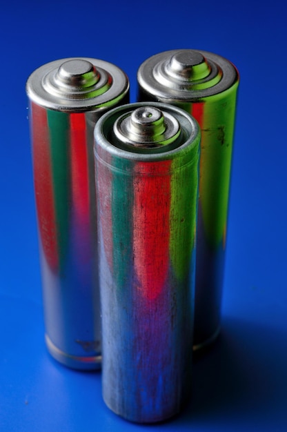 Three penlight batteries on a blue background. close-up