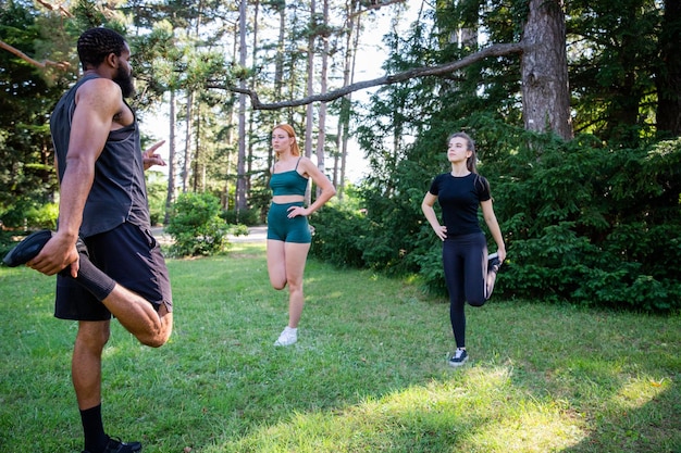 Three people are stretching in a park during a workout together healthy lifestyle