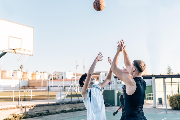 Three people jumping to catch the ball during a kick-off in a basketball game in an outdoor court