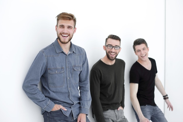 Three people leaning against the wall smiling