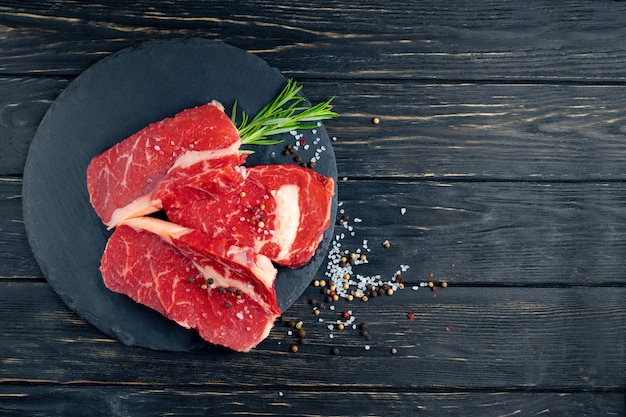 Three pieces of juicy raw beef on a stone cutting board