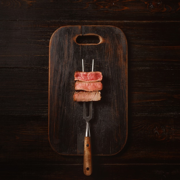 Foto tre pezzi di carne su una forchetta per carne. tre tipi di arrosti di carne, rari, medi, ben cotti.