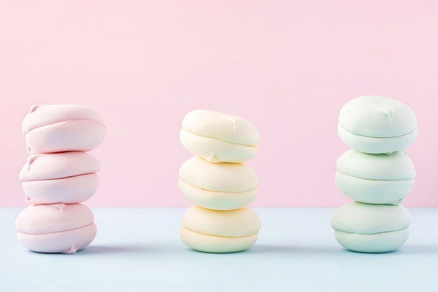 Three piles of colorful marshmallows on pastel pink and blue background