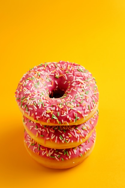 Three pink donuts on yellow  top view copy space