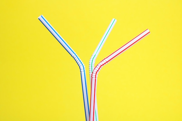 Three plastic straws for drink on yellow background