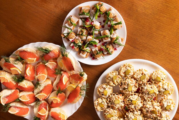 Three plates with delicious snacks and appetizers on a wooden table in a cafe