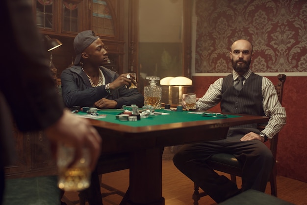 Photo three poker players with whiskey and cigars sitting at the table