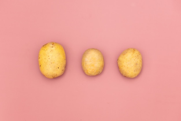 Three potatoes on pink background