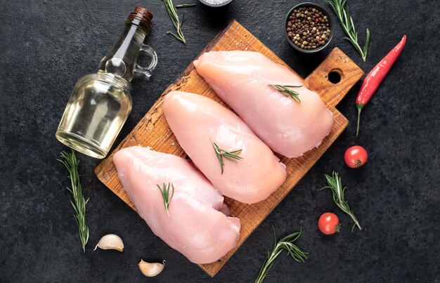 Three raw chicken breasts on stone background