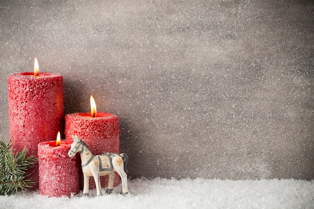 Tre candele rosse sulla superficie grigia, decorazioni natalizie. atmosfera d'avvento.