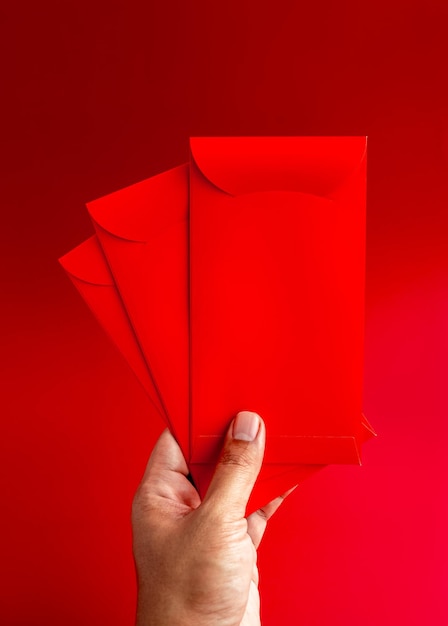 Foto tre buste rosse tenute a mano isolate su sfondo rosso stile verticale 3 pacchetti hongbao per regalo di denaro fortunato nel capodanno lunare cinese il mese di gennaio pacchetto rosso matrimonio