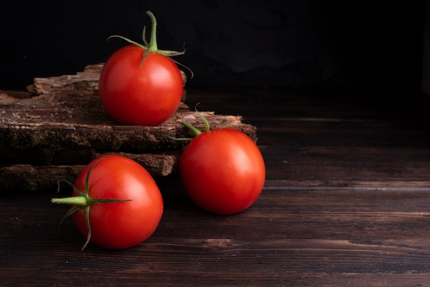 Three red fresh tomato on wooden table.