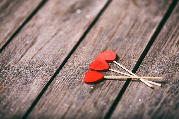 Foto tre cuori rossi modellano sul bastone sopra fondo di legno. concetto di san valentino