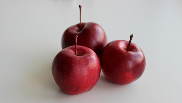 Три красных сочных яблока, изолированные на белой детализированной фотографии