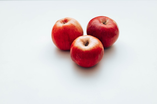 Three red juicy apples on white table. Space for text