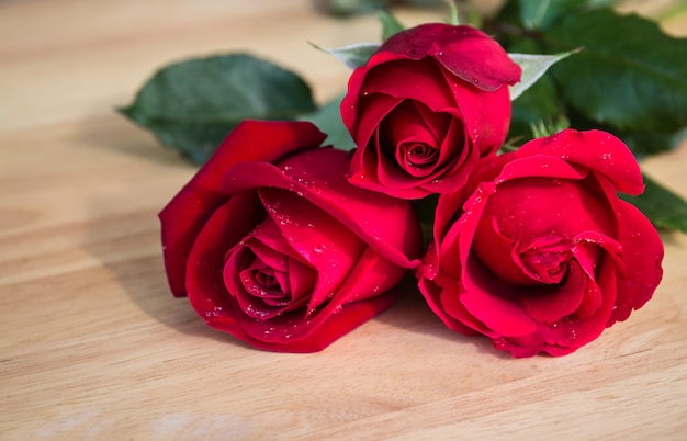 Three red rose on wood background