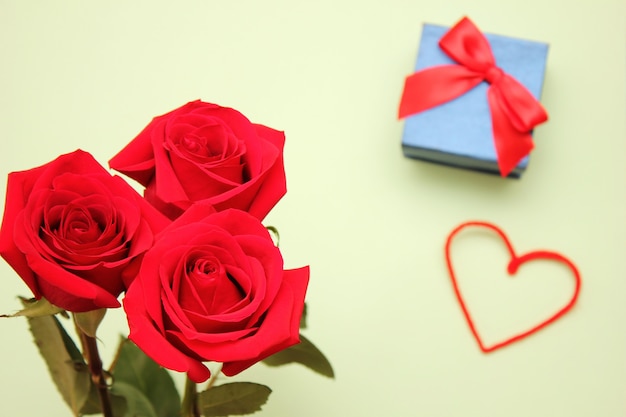 Three red roses, heart and the gift box with a bow