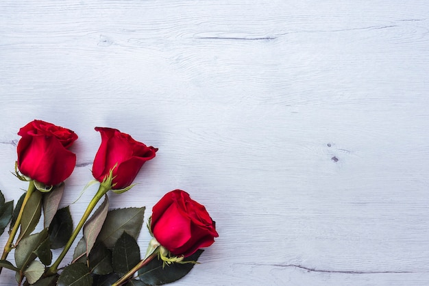 three red roses, on wooden table, copy space