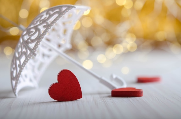 Three red wooden hearts under an umbrella