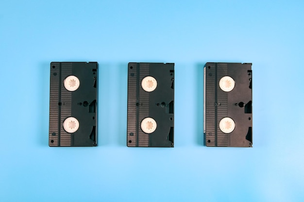 Three retro videotapes lie in the middle on a blue