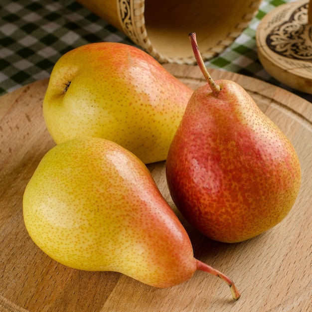 Three ripe organic pears on a wooden round  Background  a tablecloth in green and white plaid