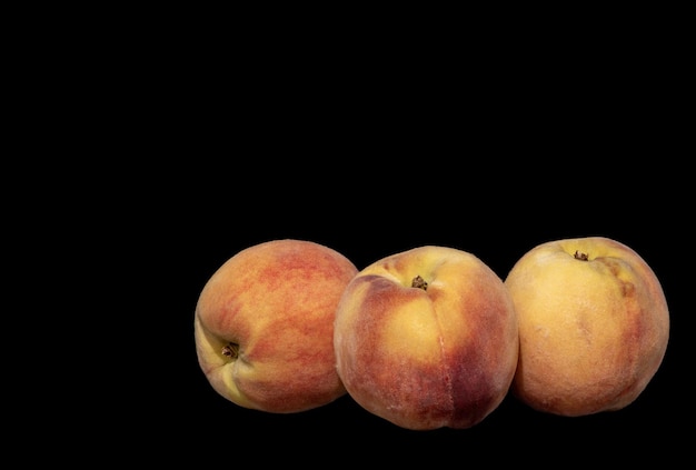 Three ripe peaches on black background