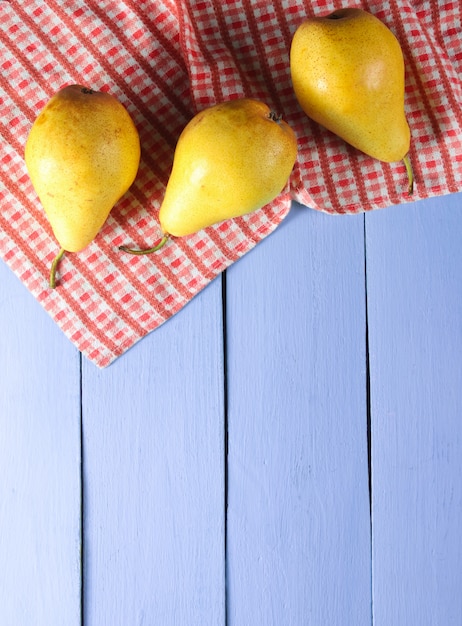 Three ripe pears with tablecloth on purple wooden. Top view. Copy space