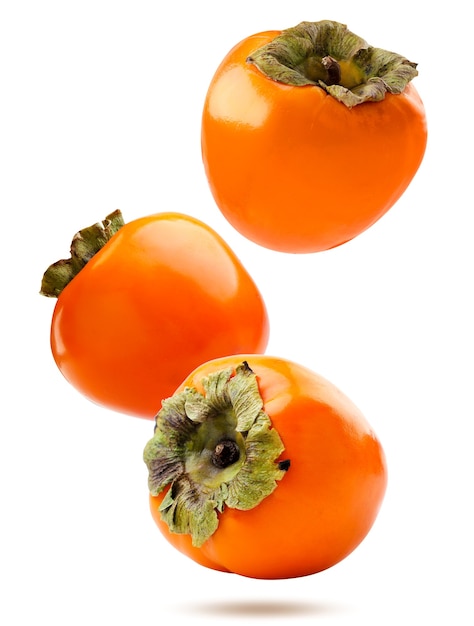 Three ripe persimmons falling on a white background. Isolated