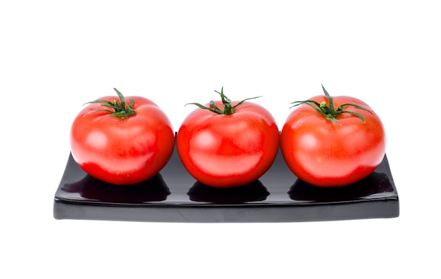 Three ripe red tomatoes on black plate