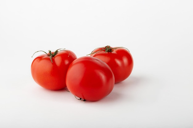 Three ripe red tomatoes on a white background