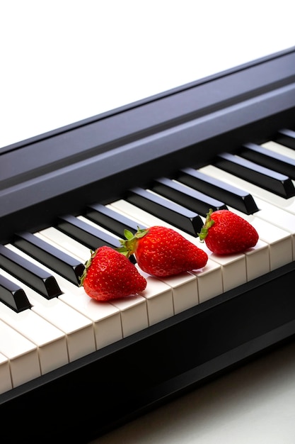 Three ripe strawberries on the piano keys