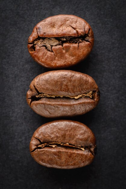 Three roasted coffee beans on a black background. Detailed macro.