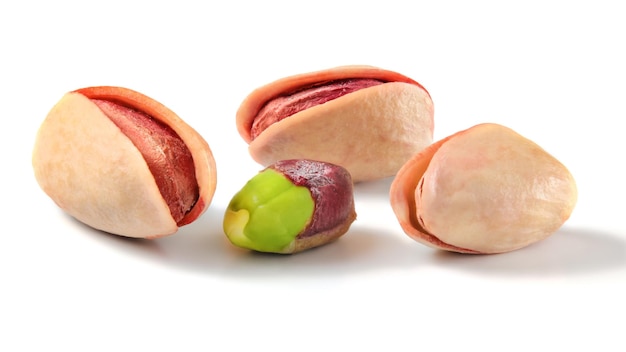 Three roasted Turkish red pistachios, and one partially peeled green nut isolated on white background