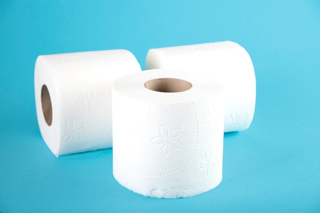 Three rolls of white toilet paper on blue