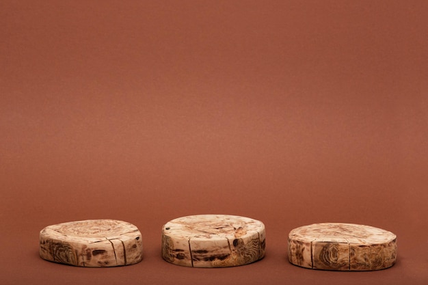 Photo three round sawn platforms or wooden podium for presentation of eco beauty cosmetics on brown background