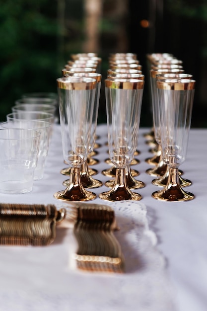 Three rows of glasses for champagne or wine and cutlery stand on table