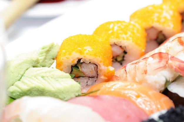 Photo three rows of sushi of a glass dish including makisushi and nigirisushi